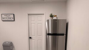 A kitchen with a stainless steel refrigerator, a trash bin, a white door, and a welcome sign on the wall. - Velvet Desire Only For adults/ 15 min Strip (Las Vegas)