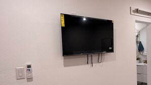 A flat-screen TV mounted on a white wall, a power outlet, and a door leading to another room. - Velvet Desire Only For adults/ 15 min Strip (Las Vegas)
