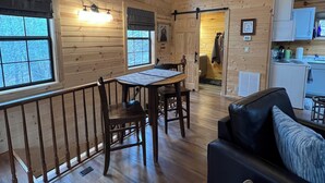 A wooden interior with a dining area, a sofa, and a kitchen. - 
Misty Spruce, tucked away, wooded for 2 guests. Honeymoon/Anniversary/Birthdays (Gatlinburg)