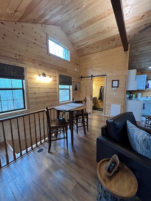 A wooden interior with a dining area, a sofa, and a kitchen. - 
Misty Spruce, tucked away, wooded oasis. (Gatlinburg)