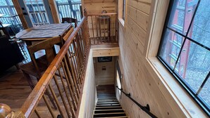 A wooden interior with a staircase, a dining area, and a view through a window. - 
Misty Spruce, tucked away, wooded for 2 guests. Honeymoon/Anniversary/Birthdays (Gatlinburg)