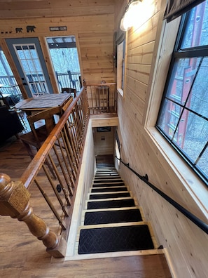 A wooden interior with a staircase, a dining area, and a view through a window. - 
Misty Spruce, tucked away, wooded oasis. (Gatlinburg)