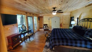 A wooden cabin interior with a bed, a desk, a chair, a wardrobe, and a television. - 
Misty Spruce, tucked away, wooded for 2 guests. Honeymoon/Anniversary/Birthdays (Gatlinburg)