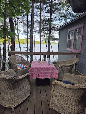 Une terrasse avec des chaises et une table en osier, donnant sur un lac.