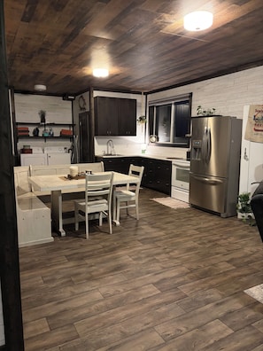 Une cuisine moderne avec un coin repas, un plancher en bois et des appareils électroménagers intégrés.