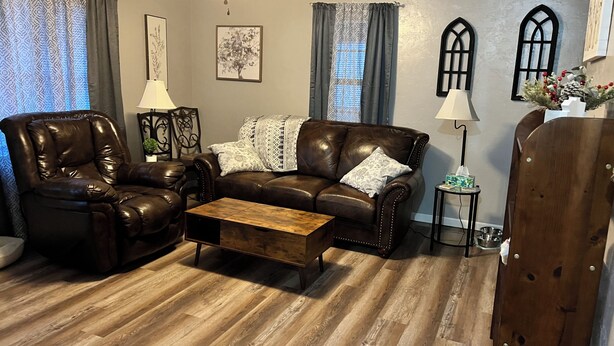 A living room with a leather sofa, a wooden coffee table, and a dining table.