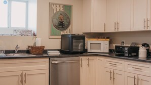 Een moderne keuken met witte kastjes, een RVS vaatwasser, een magnetron en een koffiezetapparaat.
