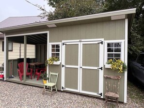 A small shed with a covered porch, a table, and chairs.