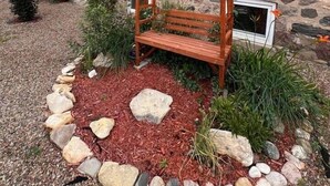 A stone building with arched windows and a wooden bench in the garden. - Charming Bed & Breakfast! 2 (Estevan)