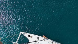 A boat docked at a marina with a clear view of the water. - Shared catamaran anchored in anse mitan bay at trois ilets (Les Trois-Îlets)