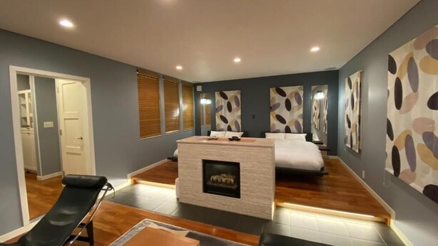 A modern bedroom with a fireplace, a bed, a bench, and abstract wall art. - Tabinoteitaku Kamakura Yuigahama (Kamakura)