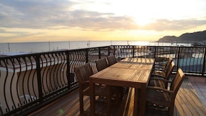 A wooden deck with a table and chairs, overlooking a beach and ocean. - Tabinoteitaku Kamakura Yuigahama (Kamakura)