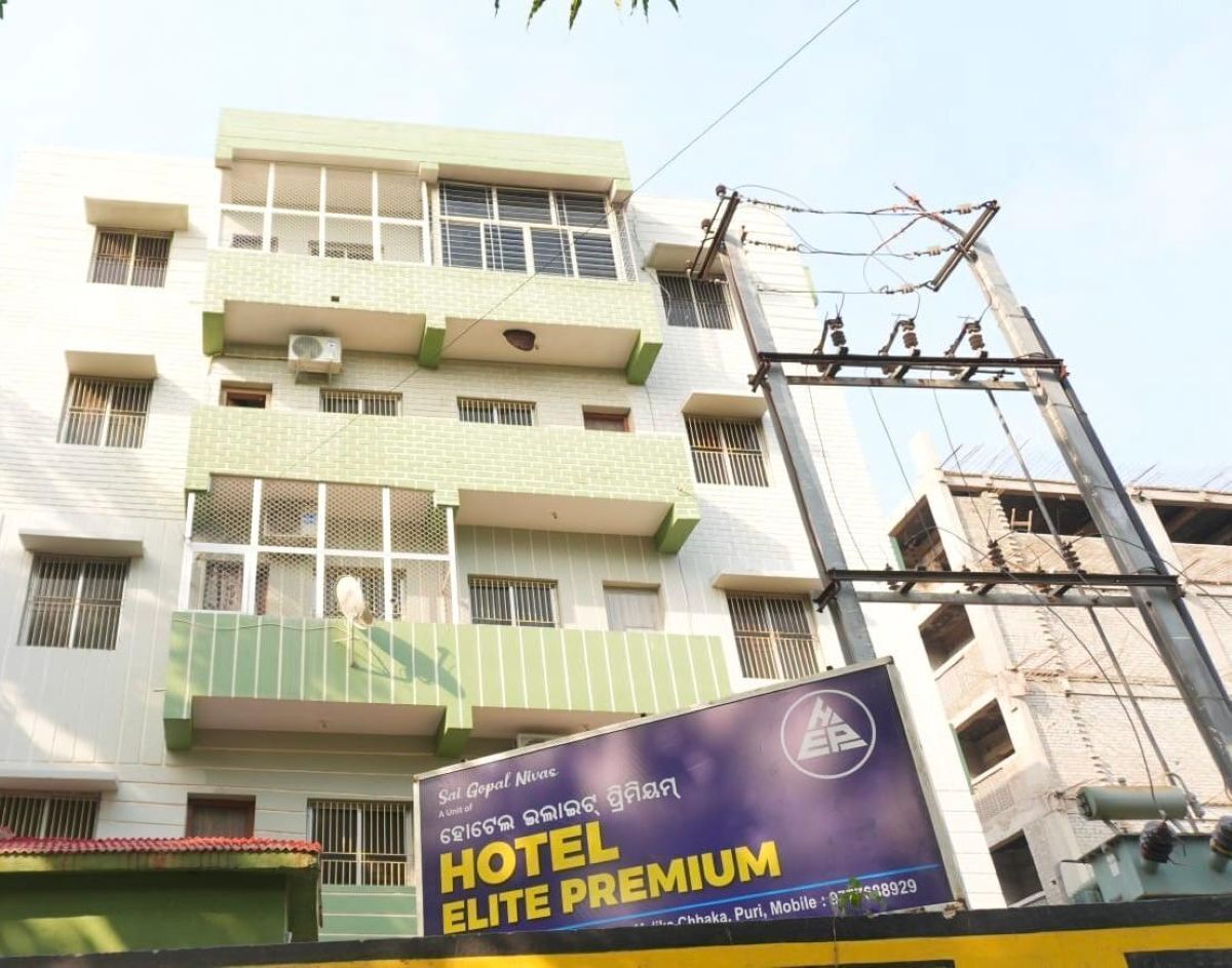 A multi-story building with balconies, a sign for 'Hotel Elite Premium,' and a partially constructed adjacent building.