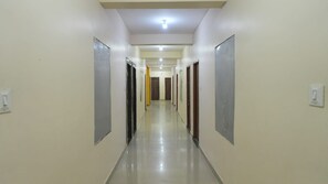 A long, narrow hallway with doors on both sides, a tiled floor, and a ceiling light. - Hotel Elite premium  (Puri)