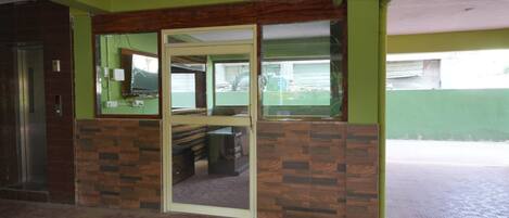 A room with a wooden accent wall, a glass door, and a visible desk with a chair.