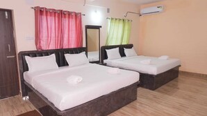 A hotel room with two beds, a mirror, an air conditioning unit, and a wooden floor. - Hotel Elite premium (Puri)