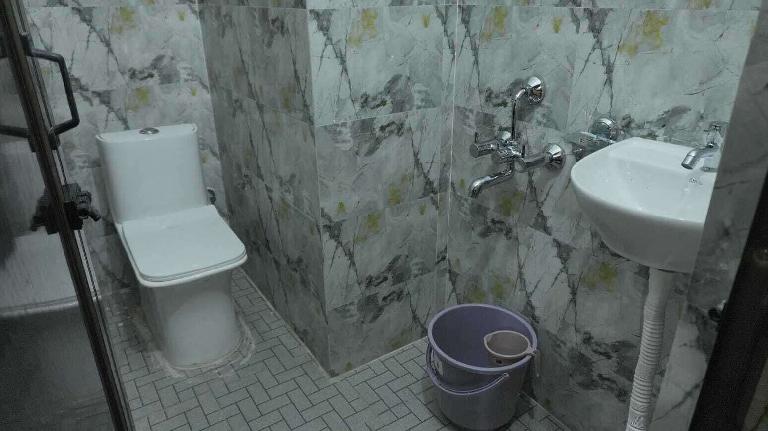 A bathroom with a toilet, a shower, and a sink.