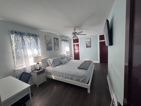 A bedroom with a bed, bedside table, lamp, and a ceiling fan.