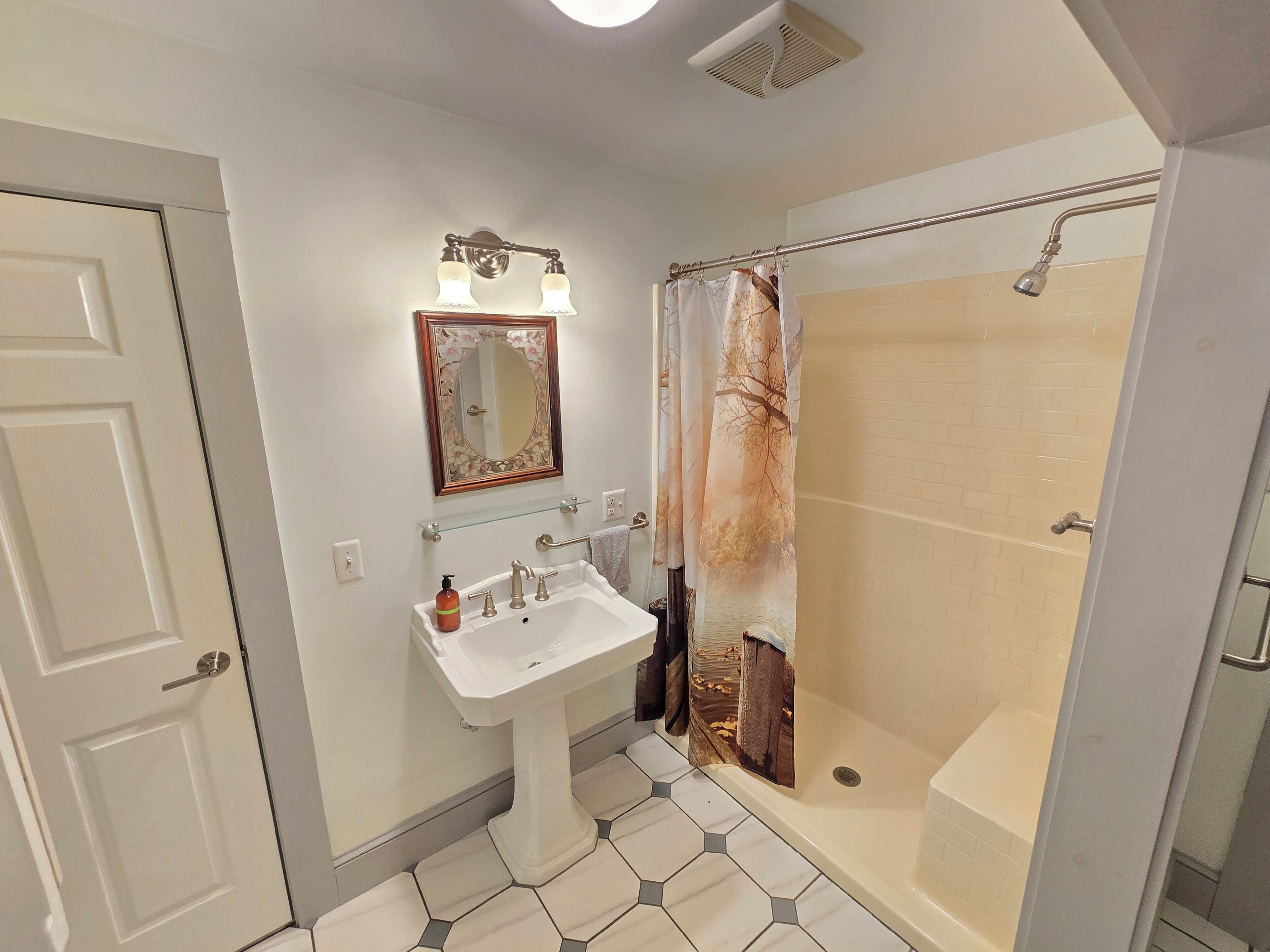 A bathroom with a white sink, mirror, and shower curtain.