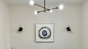 Un salon avec un canapé bleu, une table basse en verre, un lustre et des lampes fixées au mur.