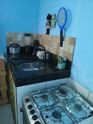 A kitchen with a gas stove, a sink, and a blue wall. - PEDRO'S LITTLE HOUSE - 100 meters from the tractor stop (Cairu)