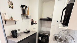 Eine kleine Küche mit einem Gaskochfeld, einer Kaffeemaschine und einem Spülbecken.