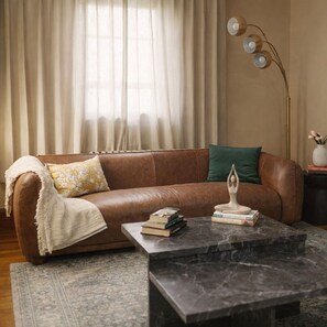A brown leather sofa with a throw blanket, a green pillow, and a marble coffee table with books. - Elegant 4BDR Boston Stay Free Garage + EV Charger (Boston)