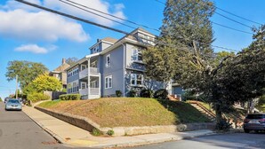 A two-story residential building with a front porch, a driveway, and a tree in front. - Elegant 4BDR Boston Stay Free Garage + EV Charger (Boston)