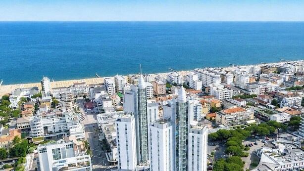 Paisagem costeira com edifícios modernos, uma praia e uma vista clara do mar.