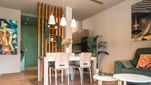 Uma área de refeições moderna com cadeiras de madeira, uma mesa branca e luminárias pendentes.