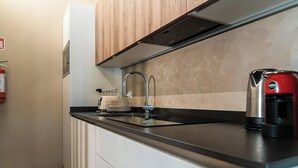 Uma cozinha com design moderno, destacando uma pia de aço inoxidável, uma chaleira vermelha e uma torradeira.