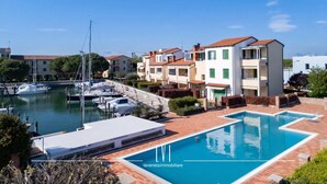 Marina com barcos, piscina e edifícios residenciais com varandas.