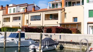 Uma marina com barcos atracados, um edifício com varandas e um céu claro.