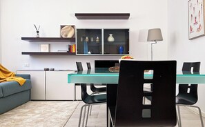 Una cocina moderna con una mesa verde azulada, sillas negras y un sofá gris.