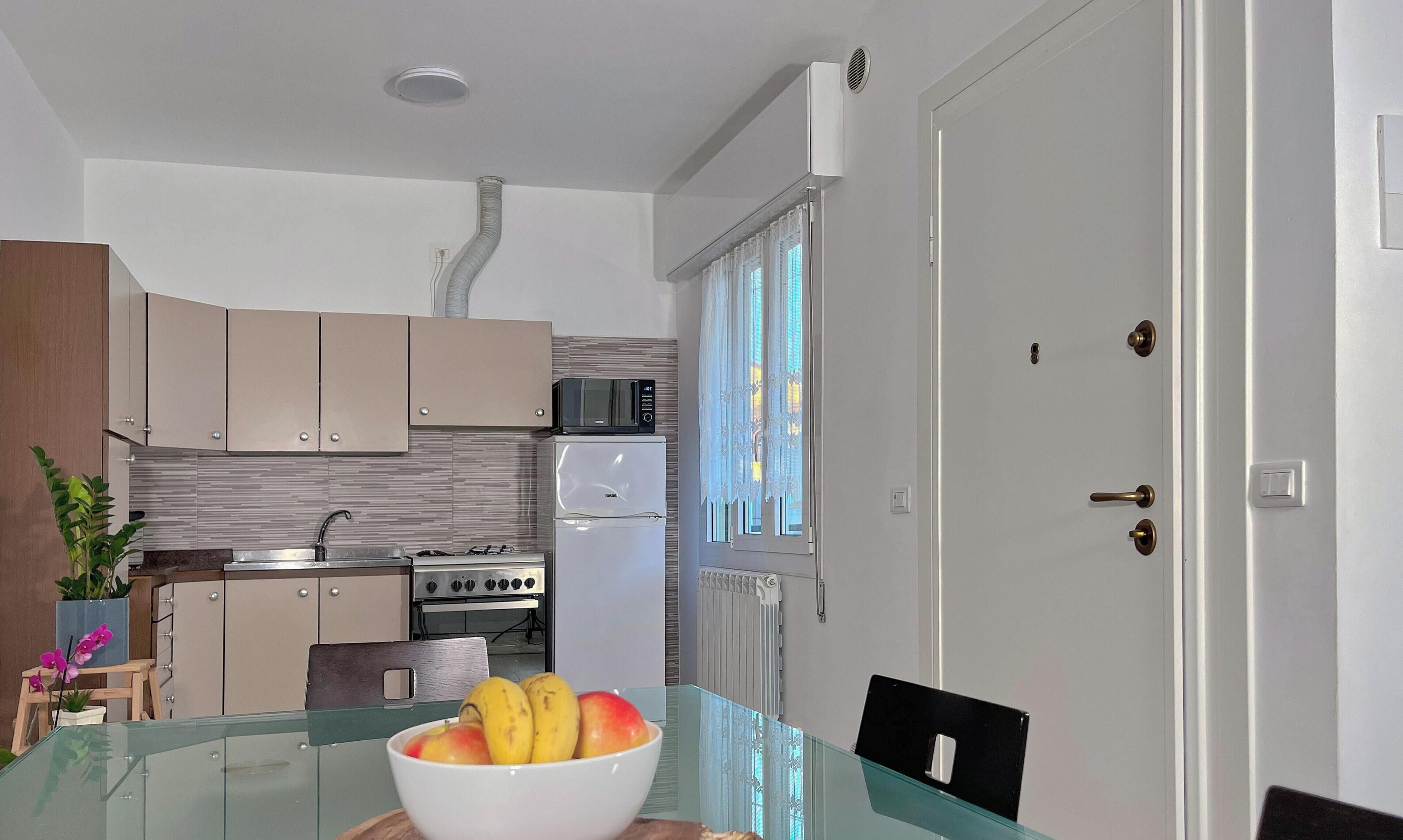 Une cuisine moderne avec une table à manger en verre, un réfrigérateur blanc, un four à micro-ondes et une cuisinière.