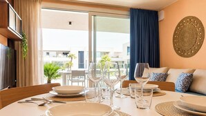 Un coin repas avec une table dressée pour quatre personnes, un canapé avec des coussins et un élément décoratif mural.