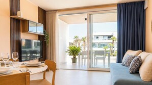 Un salon moderne comprenant un coin repas, un téléviseur à écran plat, un canapé agrémenté de coussins à motifs et une vue sur la terrasse extérieure.