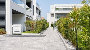 Un bâtiment moderne doté d’une allée pavée, d’une entrée fermée par un portail et de verdure de part et d’autre.