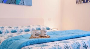 Ein Bett mit einer blauen Steude und zwei weißen Tassen mit Aufschriften.