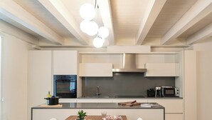 Een moderne keuken met inbouwapparatuur, een centraal eiland en een hanglamp.