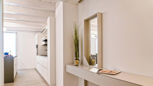 Een moderne keuken met witte kasten, een glazen vaas met planten en een tijdschrift op het aanrecht.