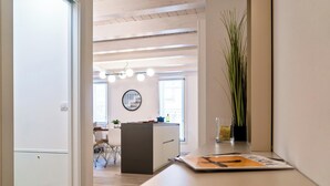 Een open doorgang naar een moderne keuken met een eethoek, een ronde spiegel en een plant op het aanrecht.