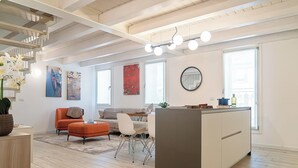 Een moderne woonkamer met een bank, een voetenbankje en een eethoek met een tafel en stoelen.