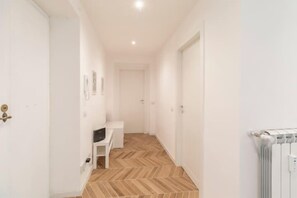 A hallway with a white door, a white radiator, and a herringbone-patterned floor. - Cocchina Residence (Roma)