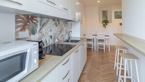 Uma cozinha moderna com armários brancos, micro-ondas e padrão de piso em espinha de peixe.