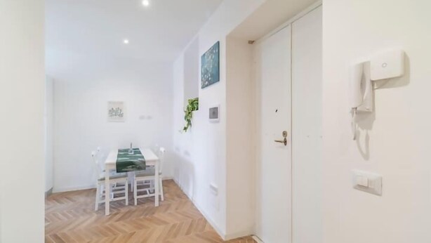 Quarto com mesa de jantar, cadeiras, guarda-roupa branco e telefone fixado na parede.
