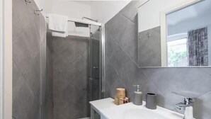 Un baño moderno con ducha, lavamanos y espejo.