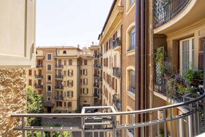 A narrow street between buildings with balconies, a metal railing, and a clear sky. - Coppedè Luxury Apartment (Roma)