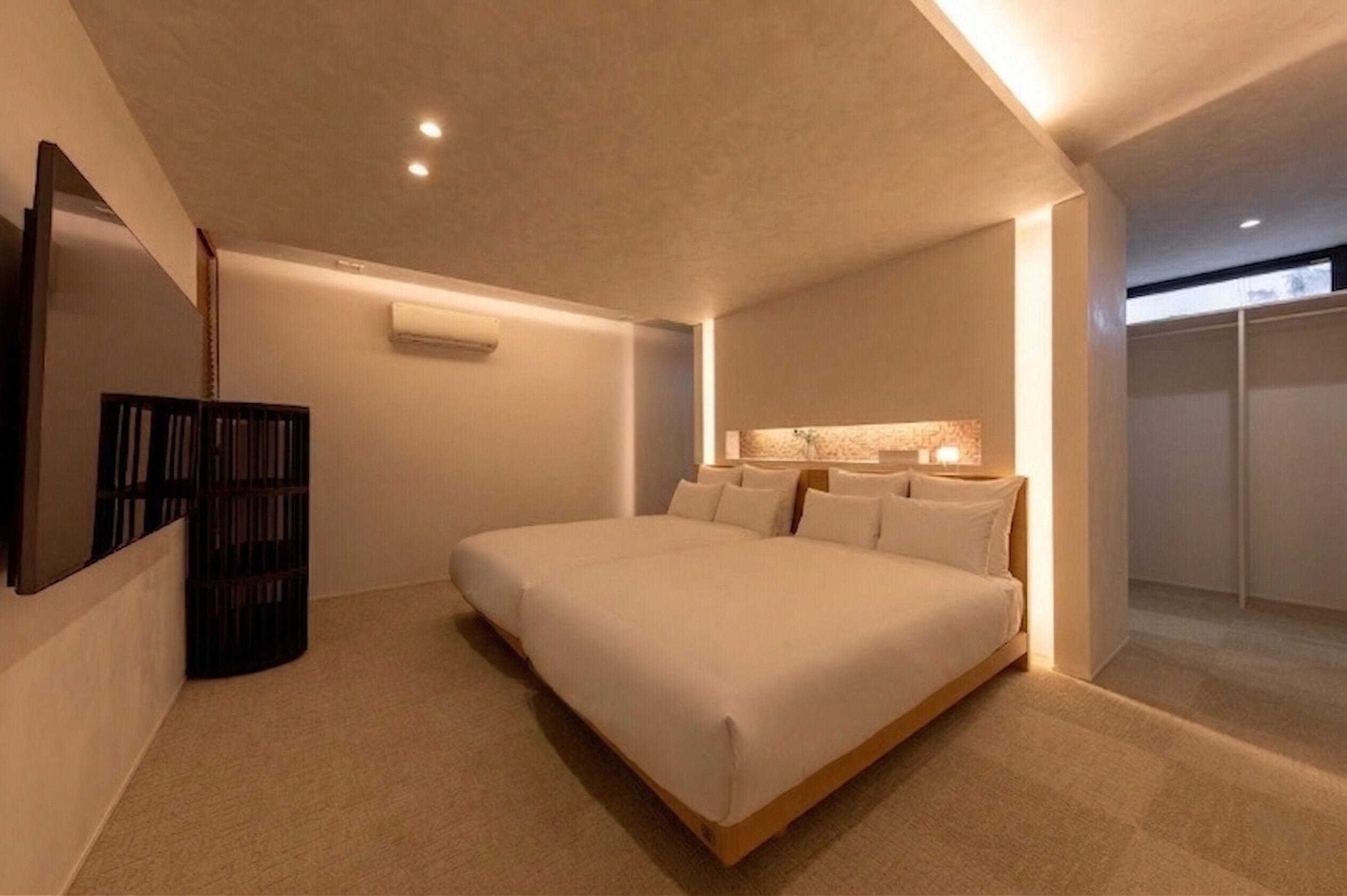 Une chambre d’hôtel moderne dotée d’un grand lit, d’un téléviseur à écran plat et d’un dressing.
