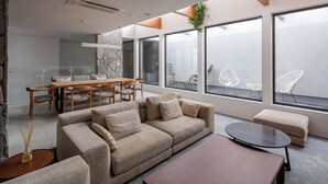 Ein modernes Wohnzimmer mit einem Ecksofa, einem runden Couchtisch und einem Essbereich mit Holztisch und Stühlen.